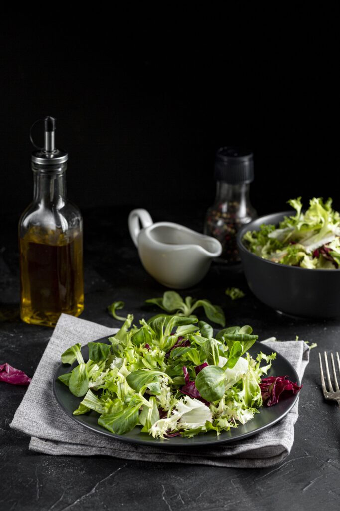 Healthy Green Salad served on white plate with lemon and much more healthy veggies